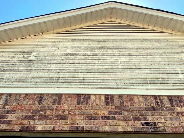 Vinyl siding gable before soft washing, streaked with mildew